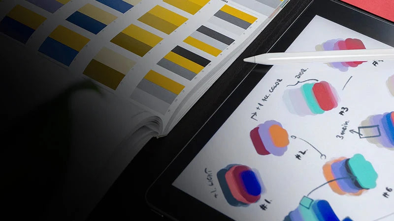 iPad screen shows color palette swatches and assets with apple pencil laying on top